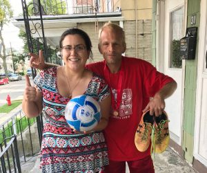 Richard holding up his soccer cleats posing next to Care Coordinator Krista holding a soccer ball.