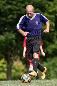Action shot of Richard kicking a ball in a Special Olympics soccer game.