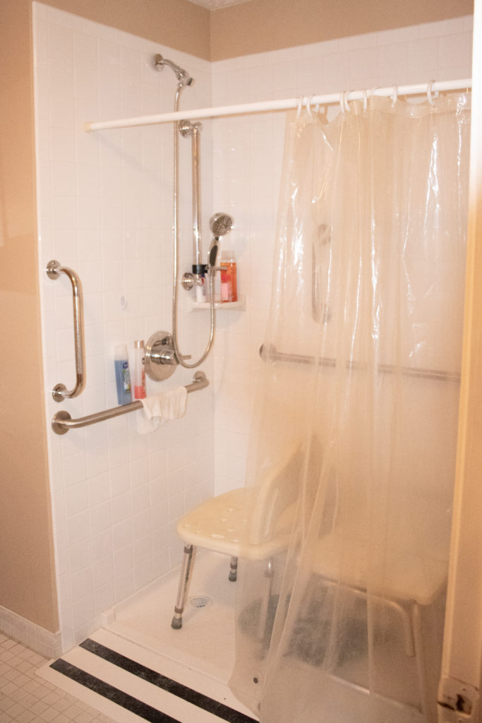 Wheelchair accessible shower with handrails and shower chair at the Romero's home.
